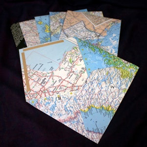 May include: A collection of vintage maps, some folded and others unfolded, with a focus on a map of Los Angeles, California. The maps are in various shades of blue, green, and brown, with black lines indicating roads and waterways.