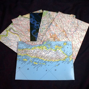 May include: A blue map of the Indonesian island of Mentawai, with the words "Kepulauan Mentawai" and "Nias" printed on the map. The map is surrounded by other maps, including a map of a city with roads and a map with a blue and black abstract design.