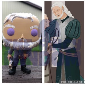 May include: A custom-painted pop figure of a man with a white beard and purple eyes. He is wearing a blue shirt and brown pants. The figure is holding a rolled-up scroll in his left hand and a small red object in his right hand. The figure is standing on a wooden surface.