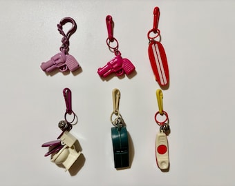 Adornos de plástico retro vintage de los años 80: monopatín rojo, inodoro, silbato y teléfono.