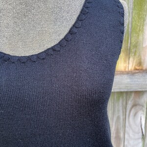 May include: A black sleeveless knitted top with a scalloped neckline.