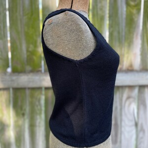 May include: A black sleeveless knitted top on a dress form.
