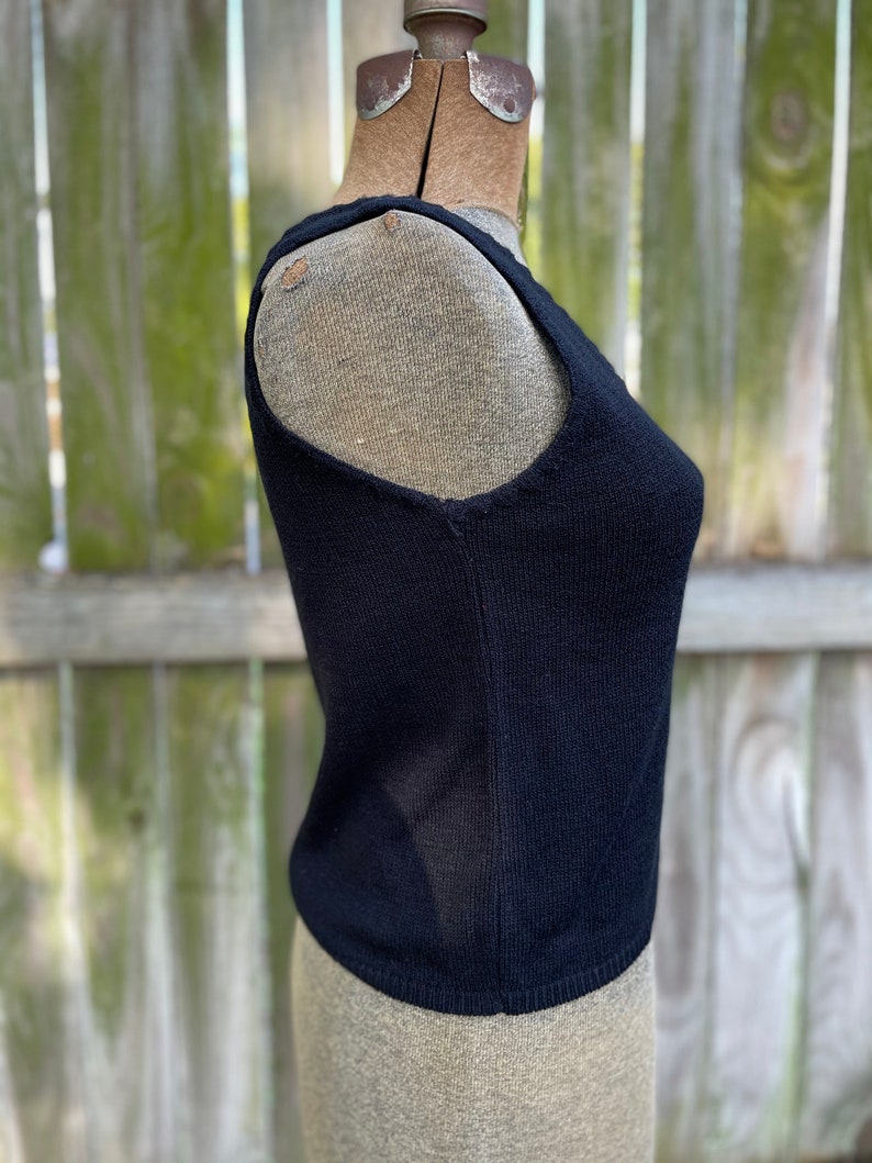 May include: A black sleeveless knitted top on a dress form.