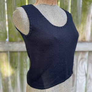 May include: A black sleeveless knitted tank top with a scoop neck.