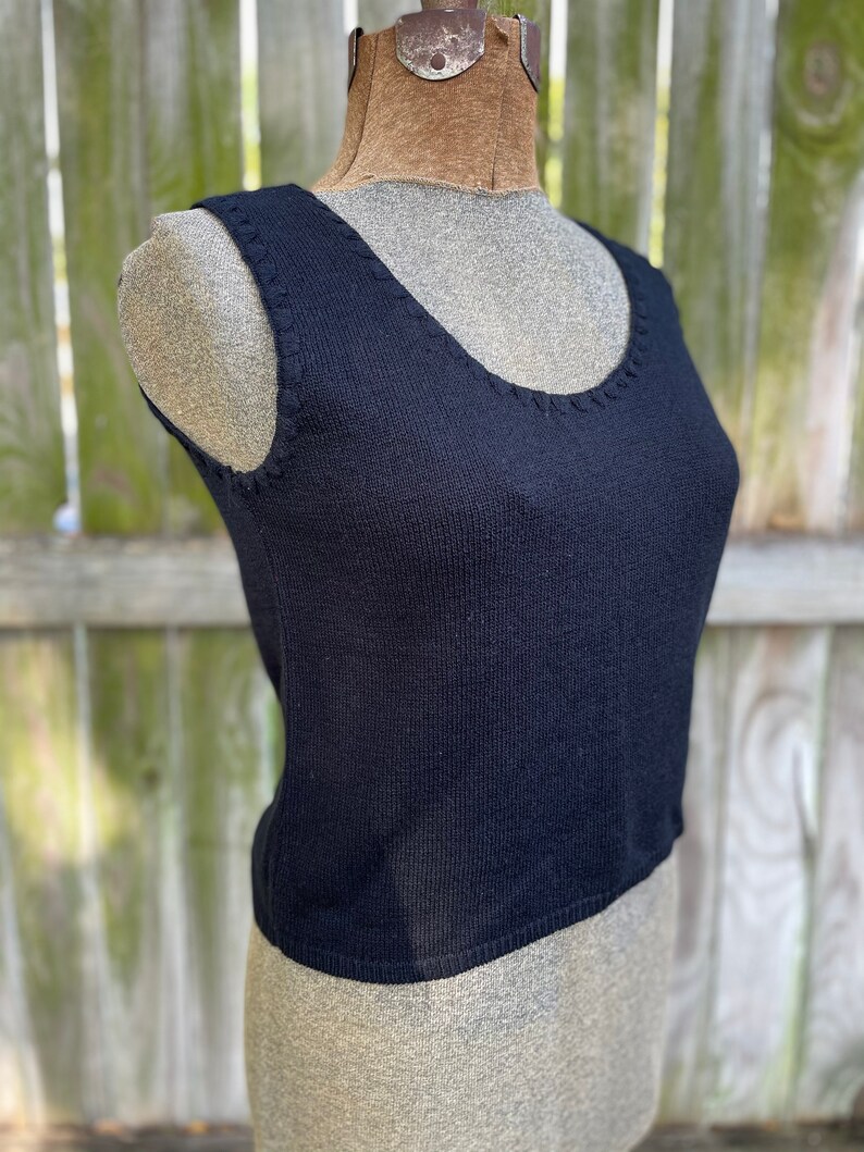 May include: A black sleeveless knitted tank top with a scoop neck.
