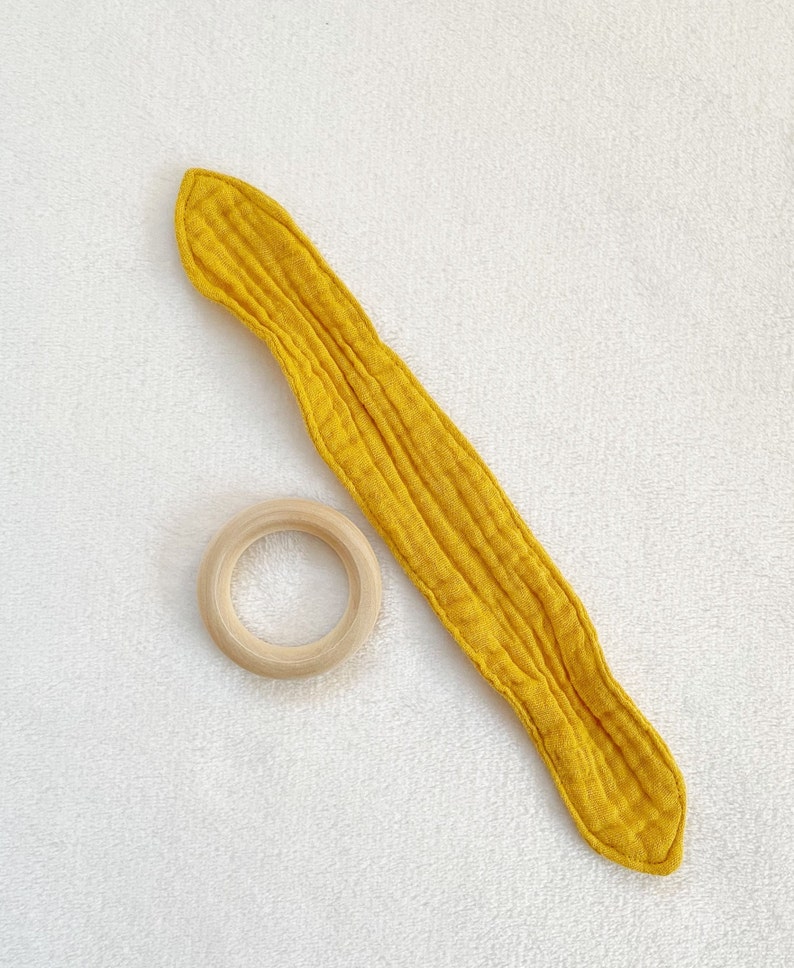 Peut inclure: Un anneau de dentition pour b&eacute;b&eacute; en tissu jaune avec un anneau en bois. Le hochet est fait d'un tissu doux et textur&eacute; et est con&ccedil;u pour &ecirc;tre s&ucirc;r pour les b&eacute;b&eacute;s &agrave; m&acirc;cher.