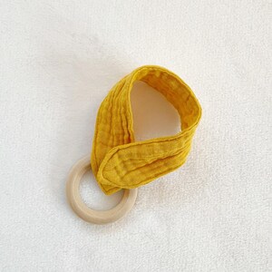 Peut inclure: Un anneau de dentition pour b&eacute;b&eacute; en tissu jaune avec un anneau en bois. Le hochet est fait d'un tissu doux et textur&eacute; et est con&ccedil;u pour que les b&eacute;b&eacute;s puissent m&acirc;cher.