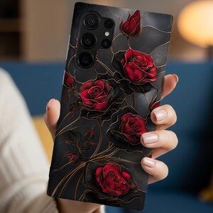 May include: A rectangular smartphone case featuring a dark black background with a pattern of deep red roses and thin gold-colored lines. The design includes multiple blooming roses and buds arranged across the surface, with a cutout for the camera lens.