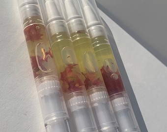 May include: Four clear plastic tubes with white caps filled with a yellow liquid and dried pink flower petals.