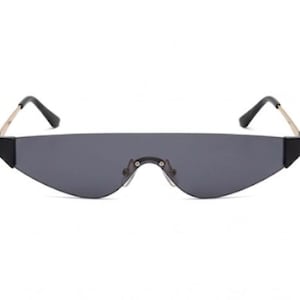 May include: Sleek, rimless sunglasses with a dark gray lens. The sunglasses have a unique, angular shape with black accents at the temples and a gold-colored arm. The design is modern and minimalist.