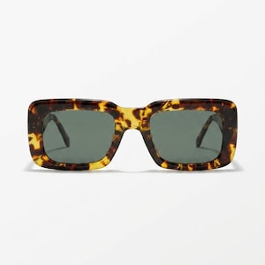 May include: Rectangular sunglasses with a tortoiseshell pattern frame and dark green lenses. The sunglasses have a thick frame and a classic, retro style. The lenses are a dark shade of green, providing protection from the sun.