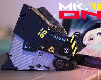 May include: A black and gray robot mask with a carbon fiber pattern and yellow and black warning stripes. The mask has a sticker that says "Face Custom" and the number "18" on it. The mask is labeled "MK.18 ONI".