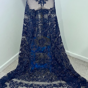 May include: Navy blue beaded lace fabric with a floral pattern. The lace is sheer and has a delicate, intricate design.