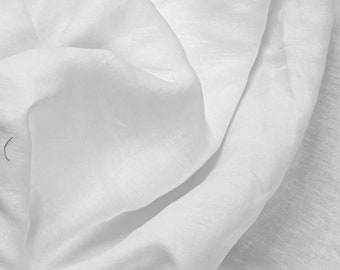 May include: White linen fabric with a smooth, soft texture. The fabric is folded and draped, showing its natural wrinkles and folds.