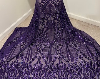 May include: Purple sequined fabric with a damask pattern. The fabric is sheer and has a delicate, intricate design.