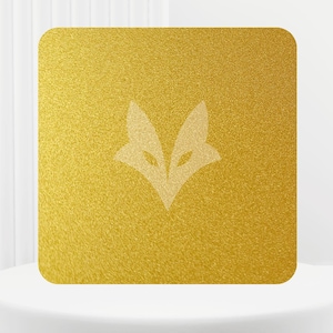 Peut inclure: Un carré doré avec une surface texturée et des coins arrondis. Un logo de tête de renard de couleur claire est centré sur le carré. Le texte "COLOR GOLD" est en haut. Le carré est sur un piédestal blanc.