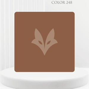 Może przedstawiać: Brązowy kwadrat z logo głowy lisa w jaśniejszym odcieniu brązu. Nad grafiką znajduje się tekst "COLOR 248". Obraz wyświetlany jest na białym, okrągłym cokole.