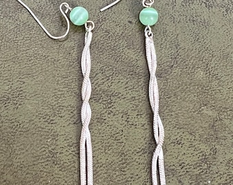 Puede incluir: Un par de pendientes de plata con una cuenta de piedra verde en la parte superior de cada pendiente. Los pendientes tienen un diseño de cadena trenzada.