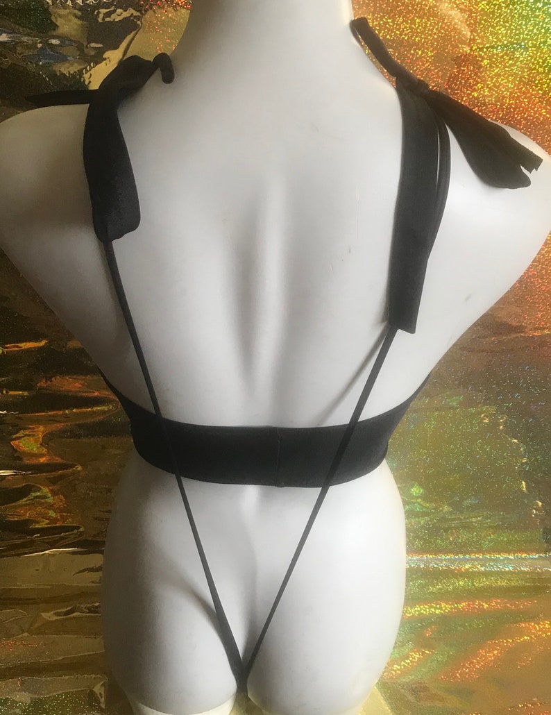 May include: Black lingerie with thin straps and a tie-back design. The straps are tied into bows at the shoulders.