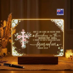 May include: An illuminated rectangular sign with a wooden base, displaying a floral cross and the words "flourishing in the house of God." The sign has a warm, inviting glow and includes the text "forever and ever." The sign is made in Australia.