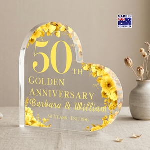 May include: A heart-shaped clear acrylic plaque featuring yellow floral accents and printed text that reads 50th GOLDEN ANNIVERSARY Barbara & William 50 Years - EST. 1976. The plaque includes a small rectangular label in the corner stating MADE IN AUSTRALIA.