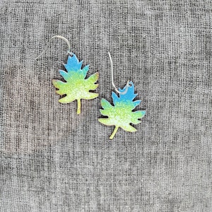 May include: A pair of earrings shaped like leaves with a gradient of blue, green, and yellow colors.