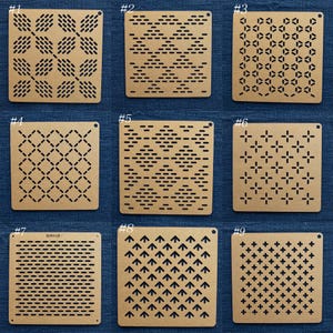 Puede incluir: Un conjunto de nueve plantillas cuadradas de color tostado, cada una con un patrón geométrico único de ranuras y formas cortadas con láser. Los diseños incluyen varias disposiciones de guiones, diamantes, cruces y flechas en cuadrícula.
