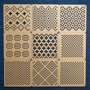 May include: Nine square wooden tiles with different geometric patterns cut out. The tiles are arranged in a 3x3 grid.