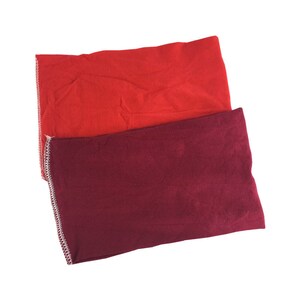Puede incluir: Dos diademas de tela, una roja y otra burdeos, con costuras blancas en los bordes.