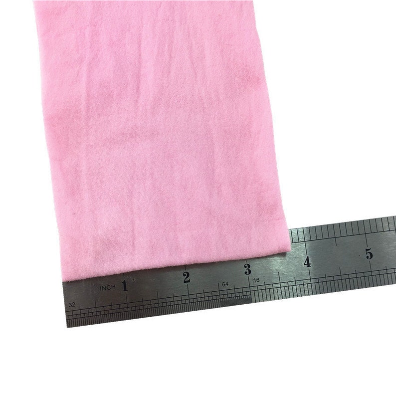 Puede incluir: Un trozo de tela rosa claro medido con una regla. La tela mide 7,6 cm de ancho.