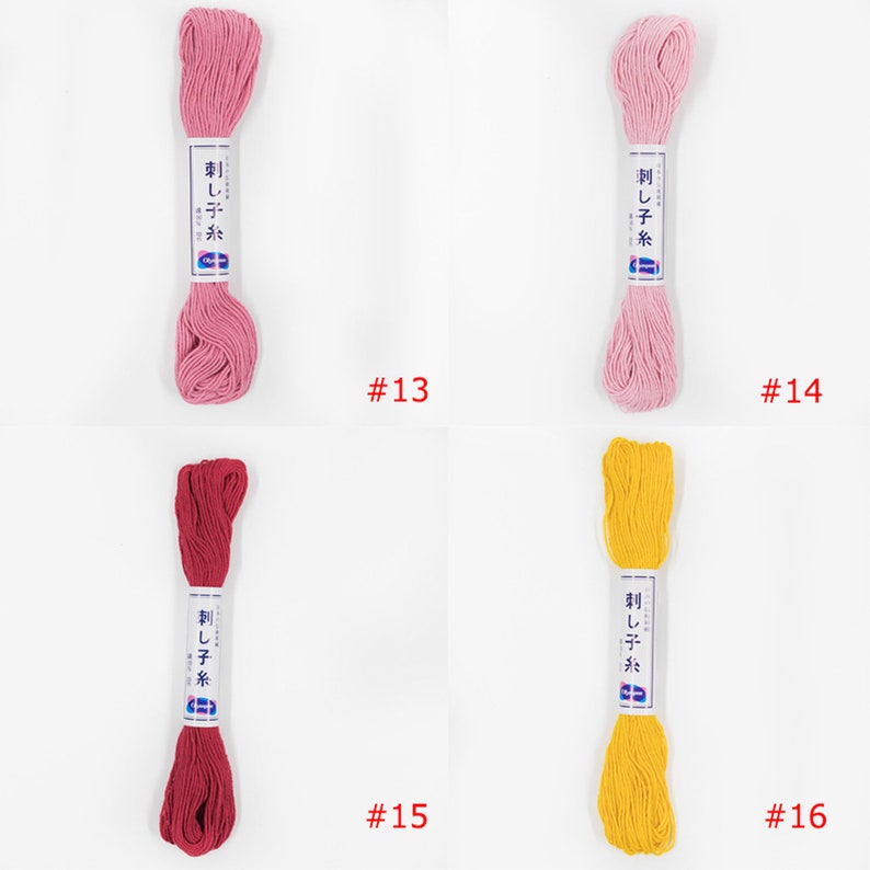 May include: Four skeins of embroidery floss in different colours: pink, light pink, red, and yellow. The skeins are labelled "刺し子糸" which translates to "Sashiko thread". The skeins are numbered 13, 14, 15, and 16.
