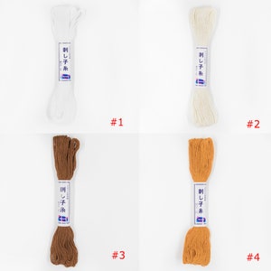 May include: Four spools of white, off-white, brown, and orange embroidery floss. Each spool is labelled "刺し子糸" in Japanese, which translates to "Sashiko thread".