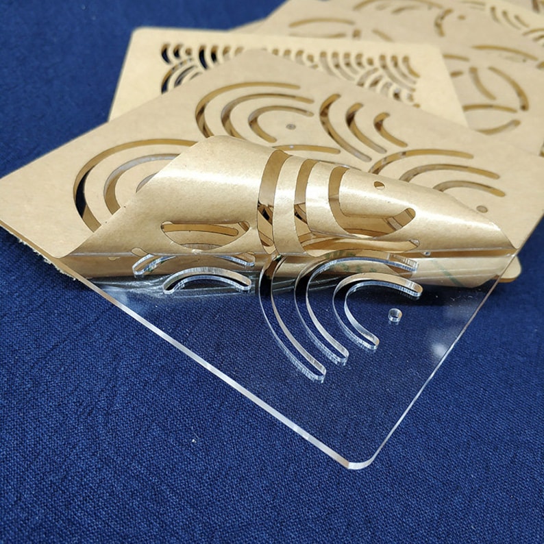 May include: A clear acrylic sheet with a pattern of concentric circles cut out. The sheet is partially covered by a brown paper sheet with the same pattern cut out.