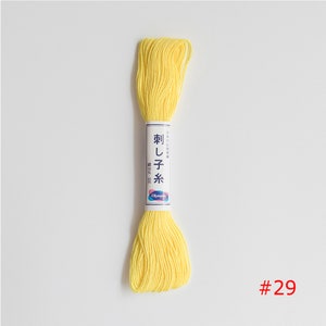 May include: A yellow embroidery floss spool with Japanese text that reads "刺し子糸" and "Olympus" on the label. The spool is labelled with the number "#29".