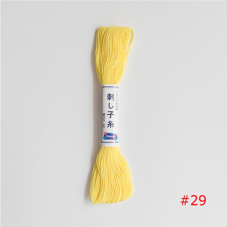 May include: A yellow embroidery floss spool with Japanese text that reads "刺し子糸" and "Olympus" on the label. The spool is labelled with the number "#29".