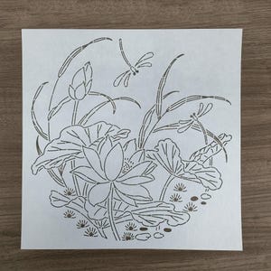 Può includere: Un disegno in bianco e nero di un fiore di loto con foglie e libellule. Il design è su sfondo bianco ed è perfetto per progetti di artigianato.
