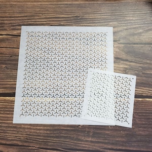 May include: Two white paper stencils with a geometric pattern of repeating triangles. The larger stencil is approximately 12 inches by 12 inches, and the smaller stencil is approximately 6 inches by 6 inches.
