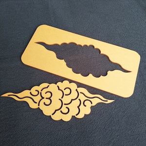May include: A set of cloud-shaped stencils and a matching cutout. The stencils are made of a light brown material and are designed with intricate cloud patterns. The cutout is a detailed cloud shape, perfect for crafting or decorative projects.