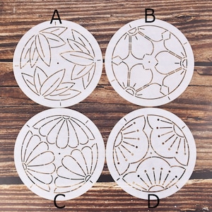 May include: Four white circular embroidery templates with different floral designs. The templates are labeled A, B, C, and D.