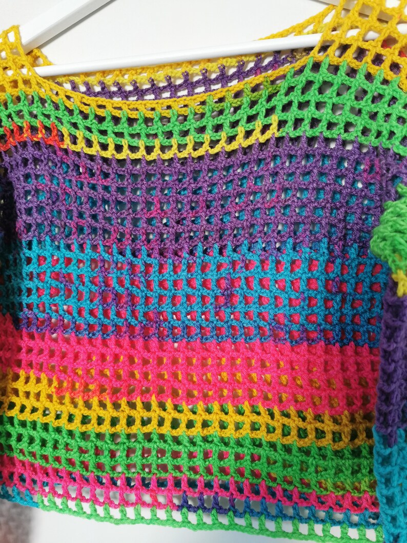 Op de afbeelding: Een regenboog-crochet top met een kleurrijk gestreept patroon. De top is gemaakt van een lichtgewicht, opengeweven stof.