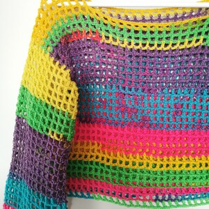 Op de afbeelding: Een regenboog gestreept gebreid topje met een losse, open structuur. De top heeft lange mouwen en een getailleerde lengte.