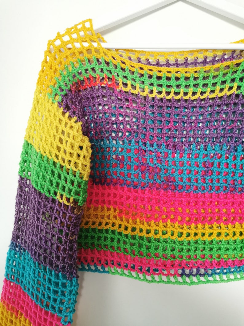 Op de afbeelding: Een regenboog gestreept gebreid topje met een losse, open structuur. De top heeft lange mouwen en een getailleerde lengte.