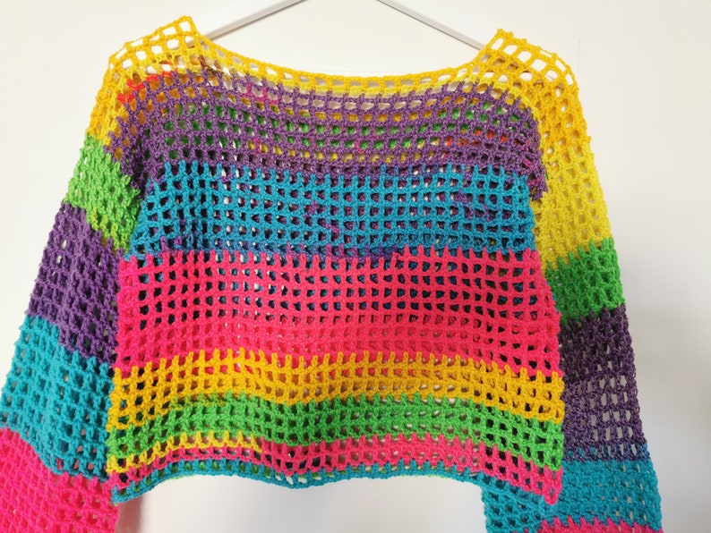 Op de afbeelding: Een regenboog gestreept gebreid topje met een losse, open structuur. De top heeft lange mouwen en een verkorte lengte.