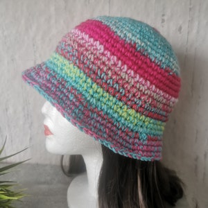Könnte beinhalten: Ein bunter gehäkelter Bucket-Hut mit Streifen in Pink, Grün, Blau und Weiß.