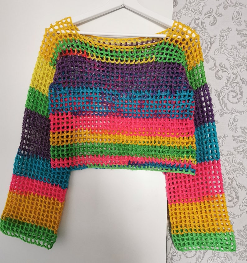 Op de afbeelding: Een regenboog gestreept gebreid topje met lange mouwen. Het topje is gemaakt van een losse, open geweven stof.