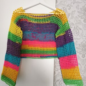 Op de afbeelding: Een regenboog-crochet top met lange mouwen en een losse pasvorm. De top is gemaakt van een lichtgewicht, ademend materiaal en heeft een kleurrijk gestreept patroon.