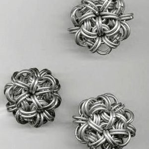 Puede incluir: Tres adornos decorativos de metal plateado en forma de flor con intrincados diseños tejidos.