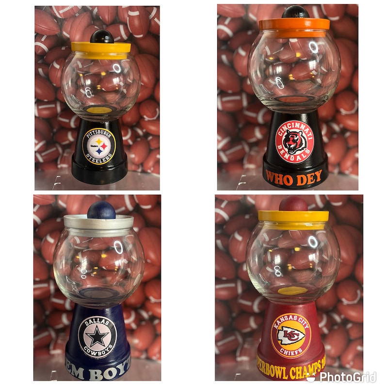 May include: Four glass candy jars decorated with different NFL team logos. The jars are painted black, red, blue, and maroon with the team logos and names. The jars are sitting on a surface with footballs in the background.
