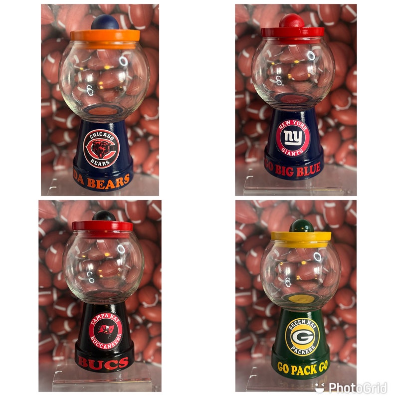 May include: Four glass candy jars with team logos painted on the bases. The jars are decorated with the logos of the Chicago Bears, New York Giants, Tampa Bay Buccaneers, and Green Bay Packers. The jars are all on a white background.