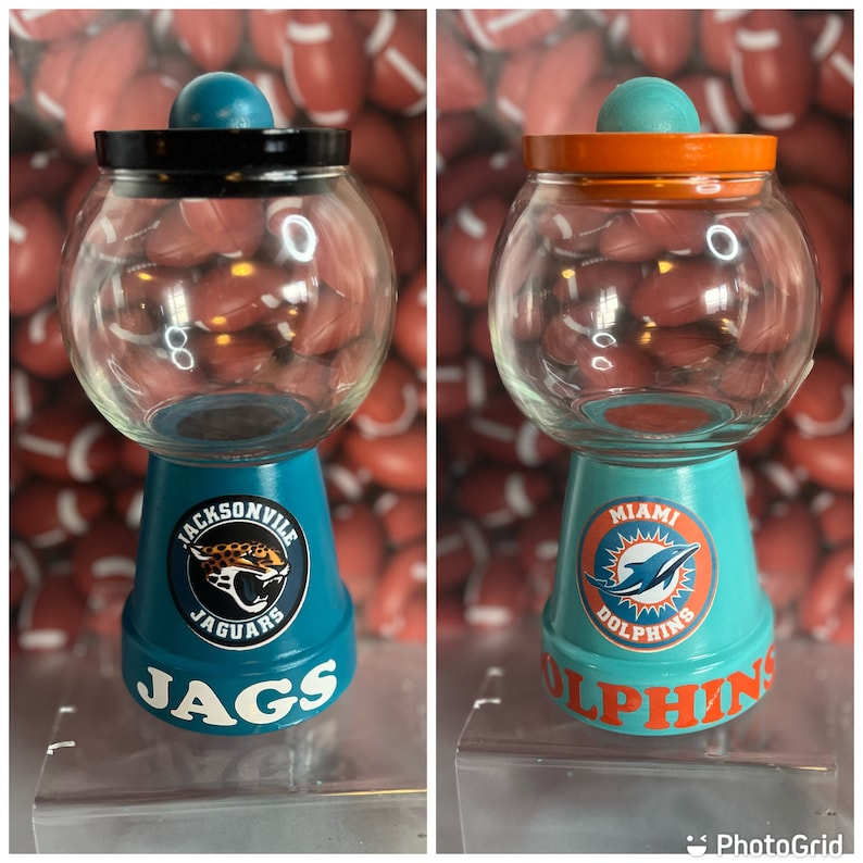 May include: Two teal blue and white ceramic candy dispensers with lids. One features the Jacksonville Jaguars logo and the other features the Miami Dolphins logo.